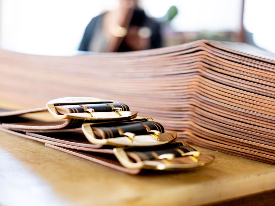 Des ceintures de cuir à boucle, sur l'établi de la Sellerie