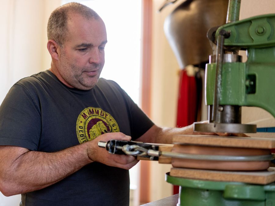 Un artisan travaille une courroie à la presse